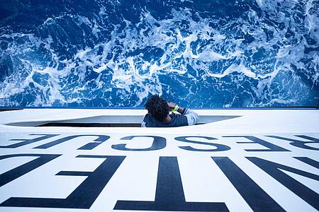 Ein geretteter Bootsflüchtling schaut von einem Bullauge auf dem deutschen Seenotrettungsschiff «Humanity 1» aus auf das Meer.