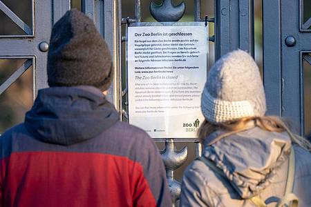 Besucher lesen den Aushang am geschlossenen Tor zum Berliner Zoo.