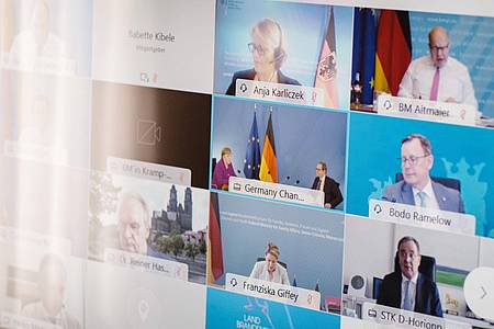 Ministerpräsidenten, Kanzlerin und weitere Vertreter der Bundesregierung sind während der Bund-Länder-Konferenz auf einem Bildschirm.
