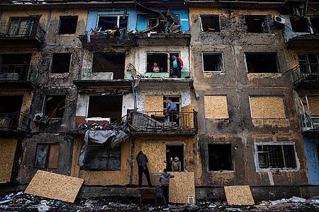 Anwohner im ostukrainischen Dobropillja verbarrikadieren nach russischem Beschuss die Fenster eines Wohnhauses mit Sperrholz.
