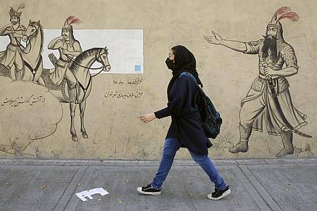 Ein Mädchen geht an einer Häuserfassade in Teheran entlang.