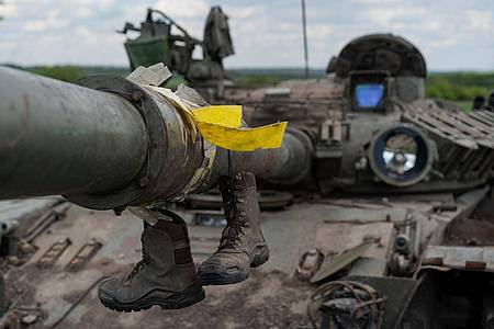 Militärstiefel hängen an einem zerstörten Panzer in Vilkhivka am Stadtrand von Charkiw.