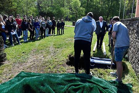 Schüler des Johannes-Sturmius-Gymnasiums lassen auf dem Friedhof in Schleiden den Sarg mit den Gebeinen ihres alten Schulskeletts ins Grab.