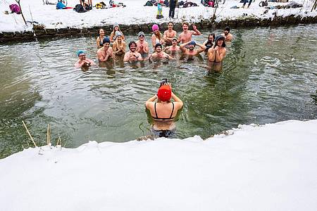 Mitglieder der Gruppe «Munich Hot Springs» baden bei eisigen Temparaturen und Schneefall in einem Nebenarm des Eisbachs im Englischen Garten in München.