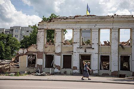 Eine Frau gehtan den Ruinen der Stadtverwaltung von Ochtyrka vorbei.
