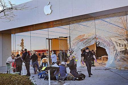 Rettungskräfte versorgen einen verletzten Kunden, nachdem ein Geländewagen in einen Apple Store gefahren ist.