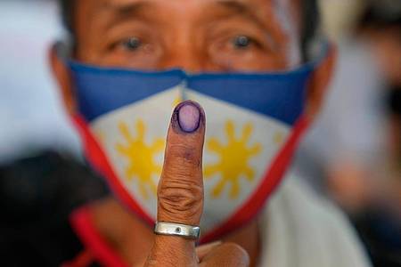 Ein Mann zeigt die Tinte auf seinem Finger, nachdem er seine Stimme im Wahllokal abgegeben hat.