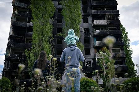 Eine Familie blickt auf ein zerstörtes Gebäude in Borodjanka.