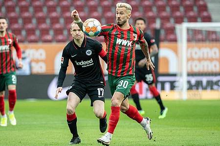 Augsburgs Niklas Dorsch (v) versucht, den Ball gegen Eintrachts Kapitän Sebastian Rode zu behaupten. Foto: Matthias Balk/dpa