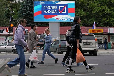 Menschen gehen an einer Anzeige mit der Aufschrift «Für immer mit Russland» in Luhansk vorbei.