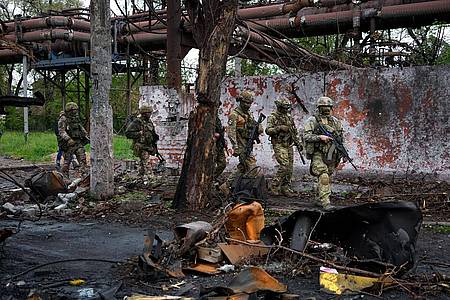 Russische Soldaten gehen durch einen zerstörten Bereich eines Eisen- und Stahlwerks in Mariupol.