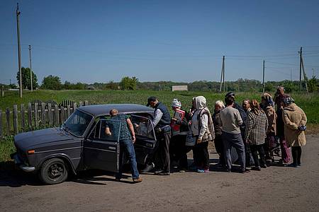 Dorfbewohner stehen Schlange, um Zigaretten und Brot in dem Dorf Staryj Saltiw in der Nähe von Charkiw zu kaufen.