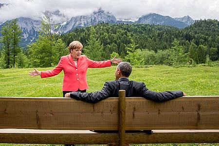 Die damalige Bundeskanzlerin Angela Merkel (CDU) spricht mit dem damaligen US-Präsidenten Barack Obama bei der G7-Konferenz 2015 auf einer Wiese bei Schloss Elmau vor der Wettersteinspitze.