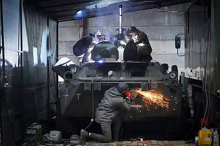 Soldaten der ukrainischen Nationalgarde reparieren einen erbeuteten russischen gepanzerten Mannschaftstransportwagen.