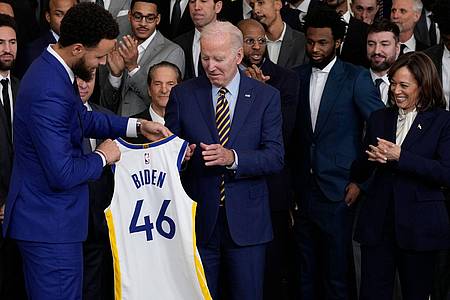 Warriors-Superstar Stephen Curry (l) überreicht Joe Biden ein Trikot.