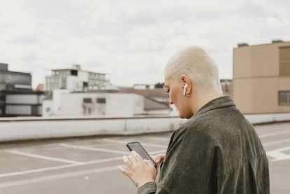 Frau mit Smartphone und Airpods-Kopfhörern