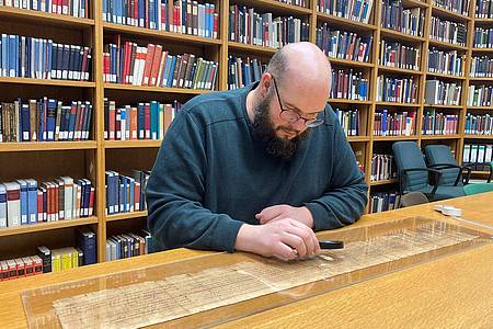Der Papyrologie-Junior-Professor Patrick Reinard studiert den Text einer Papyrus-Rolle an der Universität Trier.