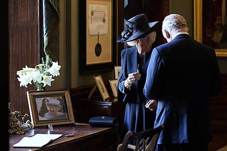 Königin Camilla hält einen Füllfederhalter, während sich König Charles III. Tinte von der Hand wischt. Der Monarch wollte sich in Hillsborough Castle in ein Gästebuch eintragen, als der Stift zu schmieren begann.