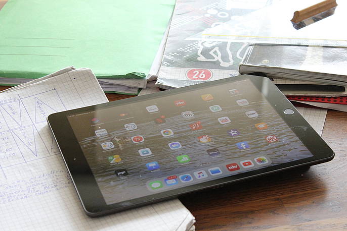 Tablet liegt auf einem Tisch umgeben von Schulbüchern und Heften