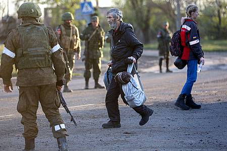 Ein aus dem Stahlwerk Asovstal entkommener Mann läuft an Soldaten der russischen Armee und der Miliz der «Volksrepublik» Donezk vorbei.