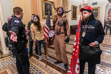Unterstützer des ehemaligen US-Präsidenten Donald Trump stehen am 6. Januar 2021 vor der Senatskammer des Kapitols. Der als Vikinger verkleidete Mann ist als Verschwörungstheoretiker in Erscheinung getreten.