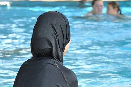 Eine muslimische Schülerin sitzt in einem Ganzkörperbadeanzug (Burkini) am Rande eines Schwimmbeckens. In Frankreich ist erneut ein Streit um Burkinis ausgebrochen.