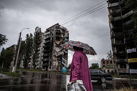 Eine Frau geht an durch Luftangriffe zerstörten Wohnhäusern an der Zentralstraße in Borodianka vorbei.