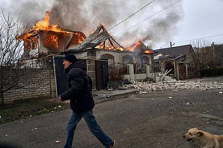 Ein Anwohner läuft an einem brennenden Haus in Cherson vorbei, das nach ukrainischen Angaben bei russischem Beschuss am orthodoxen Weihnachtsabend getroffen wurde.