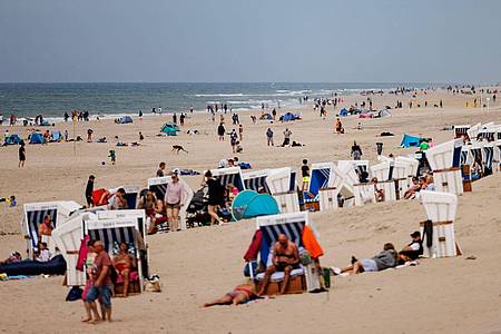 Besucher der Insel Sylt liegen in der strahlenden Sonne am Strand.