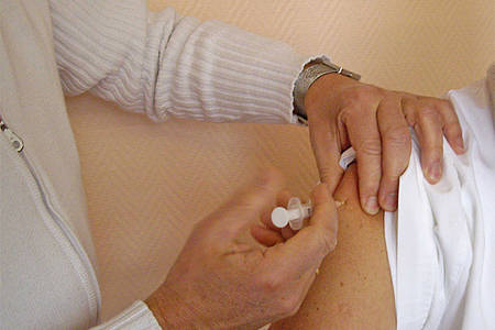 Eine Person bekommt per Spritze eine Impfung