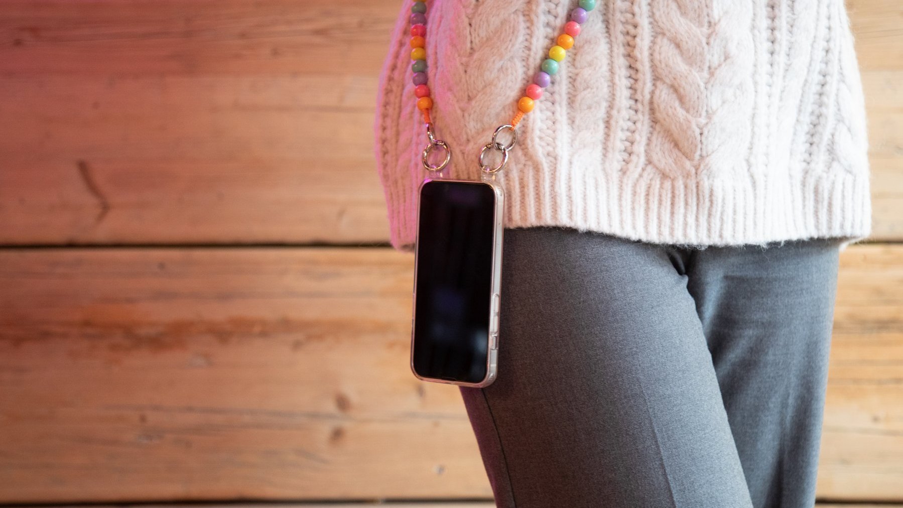 Frau hat Smartphone an bunter Handykette umgehängt.