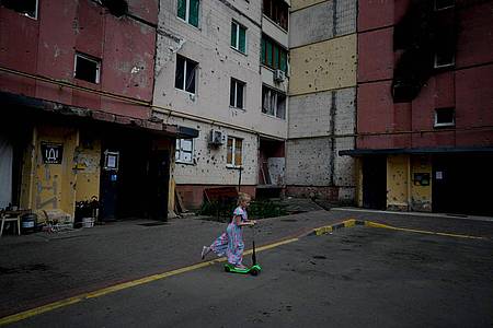 Ein Mädchen spielt im Hof eines zerstörten Gebäudes in Irpin.