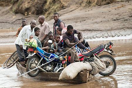 Nach dem Zyklon transportieren Männer in Malawi ihre geretteten Habseligkeiten mit einem Holzboot.