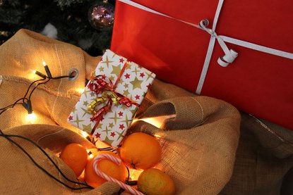 Weihnachtsgeschenke und Orangen mit Lichterkette auf Jutesack