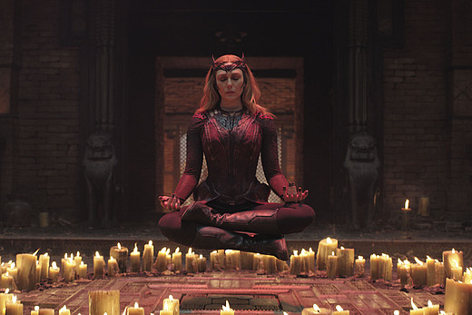 Die rote Hexe Wanda meditiert schwebend über einem Ring aus Kerzen.