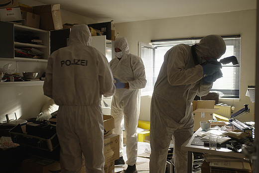 Drei Kriminalbeamte in hygienischen Überzügen dokumentieren das Zimmer von Maximilian Schmidt, dem Protagonist der Doku Shiny Flakes.