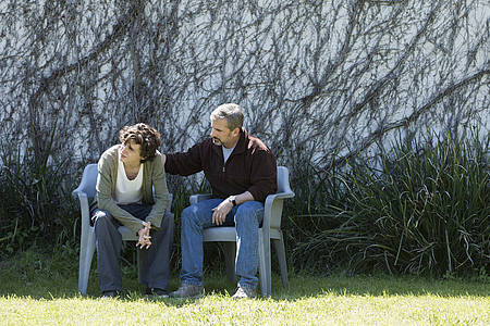 Hauptprotagonisten Nic und David sitzen auf einer Bank vor einer überwucherten Wand.