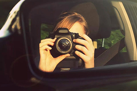 Frau fotografiert sich selber im Autospiegel